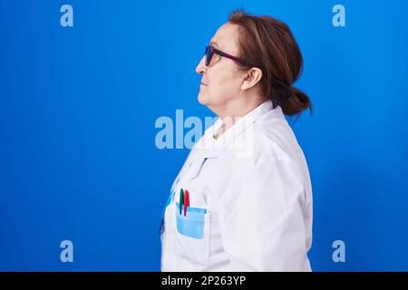 Senior woman with glasses wearing scientist uniform looking to side, relax profile pose with natural face with confident smile. Stock Photo