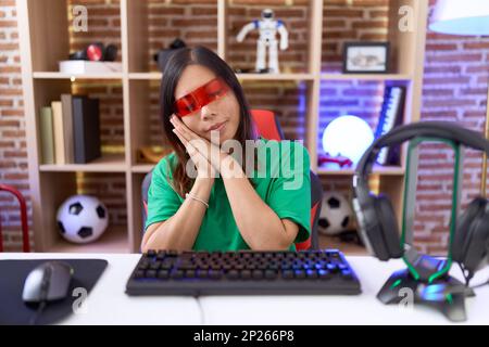 Middle age chinese woman wearing virtual reality glasses sleeping tired dreaming and posing with hands together while smiling with closed eyes. Stock Photo