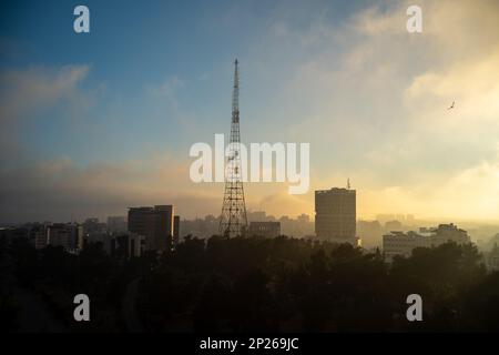 Dark Dramatic Ramallah Cityscape at Dawn with Sunrise, High Tower, Buildings, and Trees Stock Photo