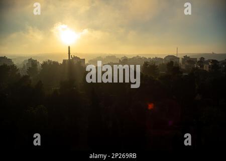 Ramallah Cityscape at Dawn with Minaret Directly in the Sunset, High Buildings and Trees Stock Photo