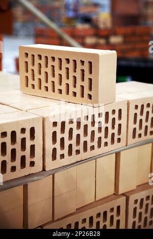 New hollow bricks stacked at warehouse for sale. Lot of yellow clay bricks close-up Stock Photo