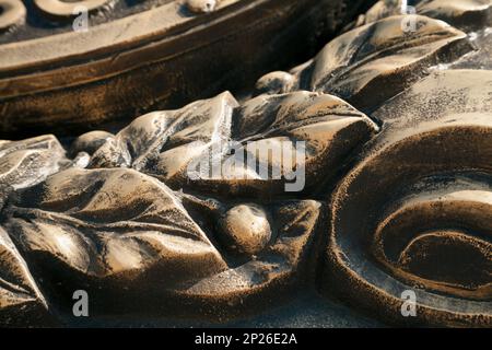 Laurel wreath  close-up dark bronze metal cast background. Vintage leaves and berries sculpture art detail Stock Photo