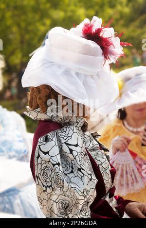 Elderly lady wearing a medieval formal dress and a hat. Mysterious old woman hiding her face. Historical female costume in a role-play Stock Photo