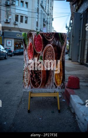 Ramallah, Ramallah and al-Bireh Governorate, Palestine, 8 July 2022: Spice-Themed Carpet Hangs on a Wooden Stand by the Sidewalk in Old Town Street Stock Photo