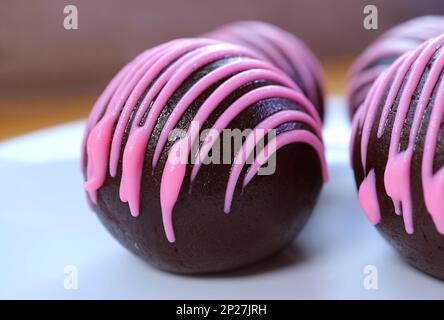 Closeup of Mouthwatering Chocolate Cake Pops Coated with Strawberry Royal Icing Stock Photo