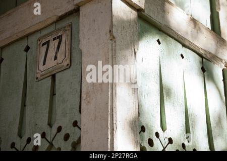 Traditional Russian wooden house with number plate close-up. Wood carved decorations  on a green rustic building. Architectural detail Stock Photo