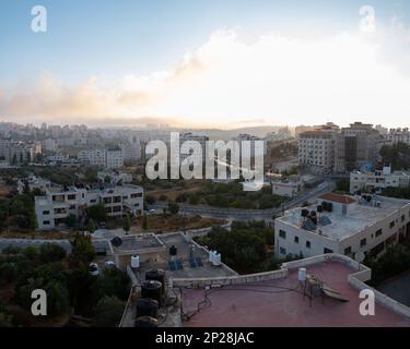 Ramallah Cityscape at Dawn with Sunset, High Buildings and Trees Facing the Sun Stock Photo