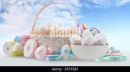 Happy Easter decorations, basket eggs with light pastel colored bright ribbons bows and string, isolated on blue sky background, banner for gift greet Stock Photo