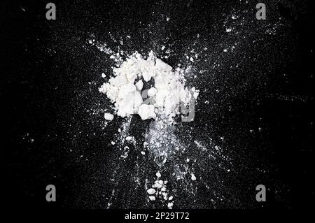 Splashing of natural white flour, powder on black board, top view as texture or background Stock Photo