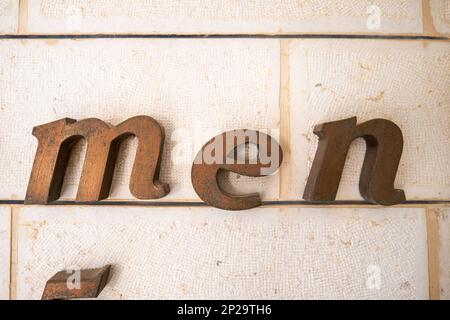 Large Golden 'men' Symbol on a White Brick Wall Stock Photo