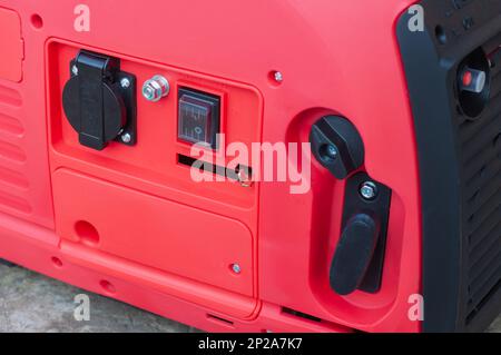 The red body of the electric gasoline generator from honda. Compact mobile voltage generator. Stock Photo