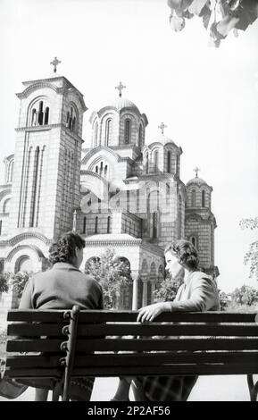 Two women are sitting on a bench in front of St. Mark's Church and are talking. Belgrade, Serbia, Europe, May 1958 Stock Photo