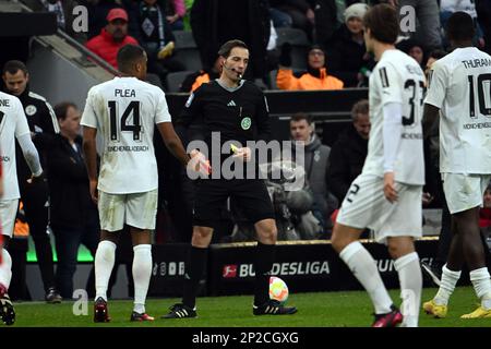04 March 2023, North Rhine-Westphalia, Mönchengladbach: Soccer: Bundesliga, Borussia Mönchengladbach - SC Freiburg, Matchday 23, Stadium im Borussia-Park. Referee Benjamin Brand puts away the red card after showing it to Ramy Bensebaini. Photo: Federico Gambarini/dpa - IMPORTANT NOTE: In accordance with the requirements of the DFL Deutsche Fußball Liga and the DFB Deutscher Fußball-Bund, it is prohibited to use or have used photographs taken in the stadium and/or of the match in the form of sequence pictures and/or video-like photo series. Stock Photo