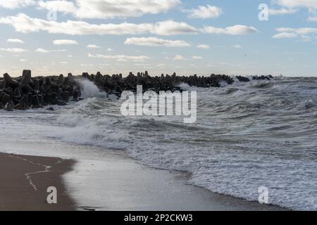 Waves crashing against breakwater consisting of gray concrete tetrapods. Liepaja, Latvia. Liepājas Ziemeļu mols Stock Photo