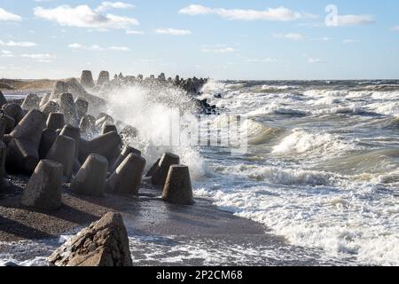 Waves crashing against breakwater consisting of gray concrete tetrapods. Liepaja, Latvia. Liepājas Ziemeļu mols Stock Photo