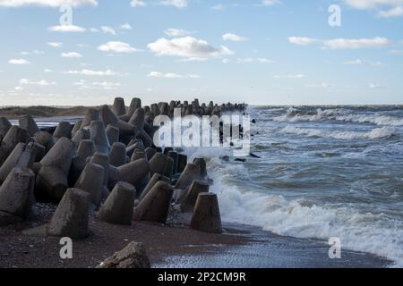 Waves crashing against breakwater consisting of gray concrete tetrapods. Liepaja, Latvia. Liepājas Ziemeļu mols Stock Photo