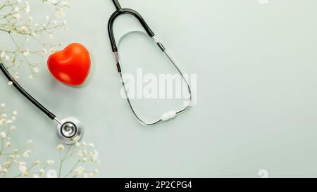 Red heart love shape hand exercise ball with stethoscope on blue background with flowers. Health care, organ donation, love and family insurance conce Stock Photo