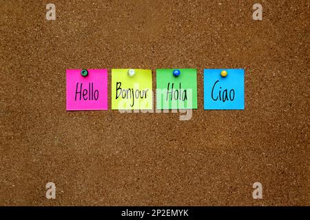 Multicolor notes with important message, motivation and reminders on cork board 'Hello' in different languages: English, French, Spanish, Italian Stock Photo