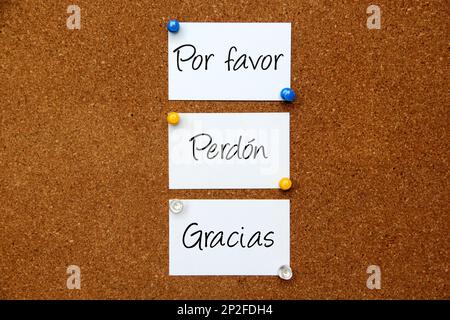 White notes on cork board with message in spanish language 'Please, Sorry, Thank you' Stock Photo