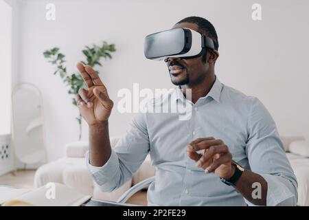 African american male developer or designer wear augmented reality glasses work with 3d objects. Professional employee of high-tech department use vir Stock Photo