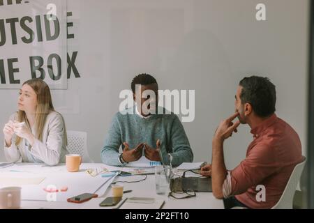 Handsome business man explaining something to his older colleague while sitting at the business meeting Stock Photo