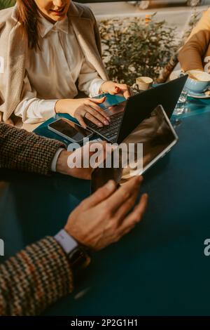 Close up of two business colleagues holding laptop and tablet while sitting at the cafe Stock Photo