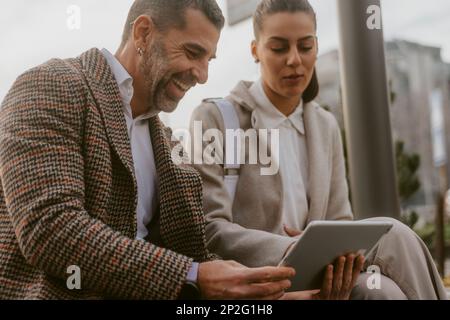Close up of older business man smiling and showing his colleague something on his tablet Stock Photo