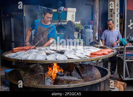 young Aboriginal men preparing a traditional food over a large bbq Stock Photo