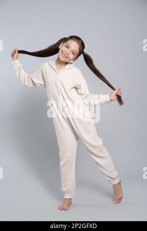 Cute girl wearing pajamas on light blue background Stock Photo - Alamy