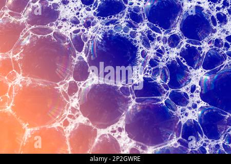 Close up, macro shot of a soap bubble, multicolored rainbow with yellow, purple, pink, blue and green colors on black background. Stock Photo