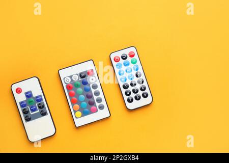 Remote controls on yellow background, flat lay. Space for text Stock Photo