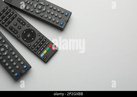 Remote controls on light grey background, flat lay. Space for text Stock Photo