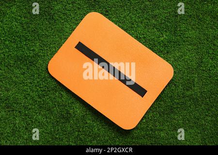 Orange foam seat mat for tourist on green grass, top view Stock Photo