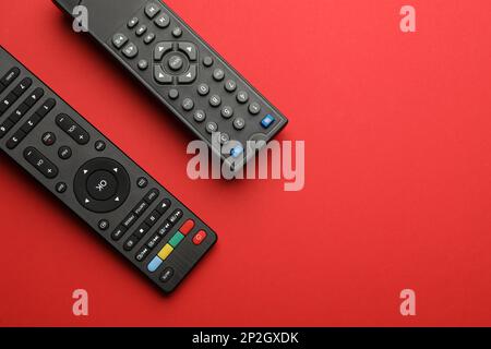 Remote controls on red background, flat lay. Space for text Stock Photo