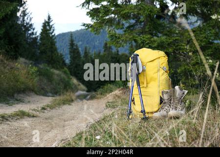Backpack, trekking poles and boots outdoors, space for text. Tourism equipment Stock Photo