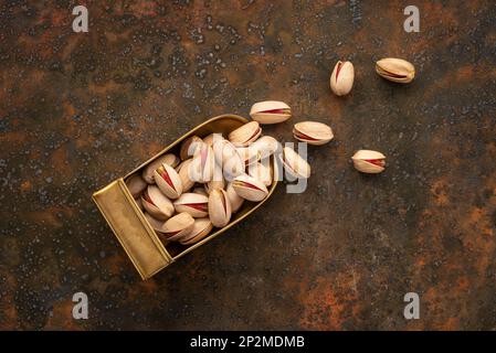 Top View of Whole Pistachios in A Brass Scoop on A Rustic Background Stock Photo