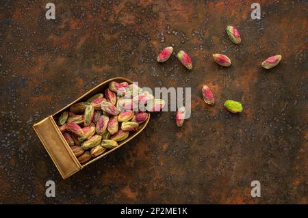 Top View of Peeled Pistachios in A Brass Scoop on A Rustic Background Stock Photo
