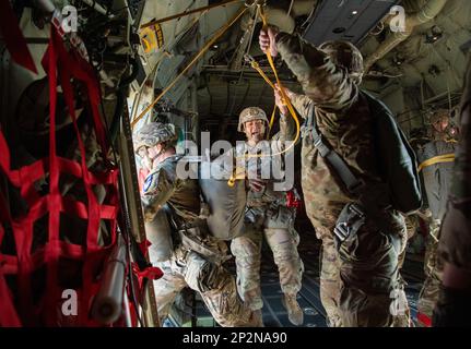 U.S. Army paratroopers from the 11th Airborne Division prepares to jump out of a C-130J Super Hercules assigned to the 36th Airlift Squadron over the Camp Narashino training area, Chiba, Japan, Jan. 8, 2023. The airborne operation consisted of three C-130J Super Hercules aircraft from Yokota Air Base, a Japan Air Self-Defense Force C-130H Hercules, a Kawasaki C-2 Greyhound and several Japan Ground Self-Defense Force CH-47JA Chinooks, which cumulatively dropped approximately 200 paratroopers. Stock Photo