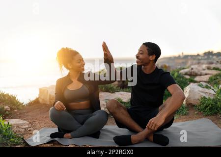 Cheerful young african american couple in sportswear enjoy workout, practice yoga, give high five Stock Photo