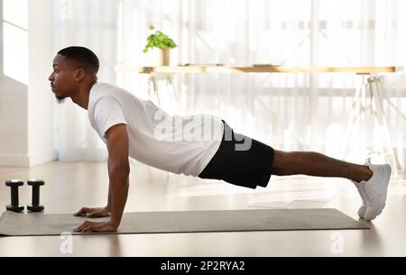 Athletic young black man doing workout at home, side view Stock Photo