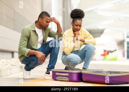 Unhappy African Couple Looking At Suitcase Having Problem In Airport Stock Photo