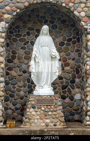Saint John, NB, Canada - May 30, 2015: A white statue of Mary in a stone alcove. She stands on a stone pedestal. The statue was erected by the Knights Stock Photo