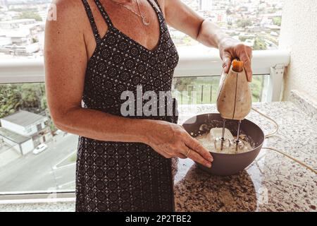 Woman using electric mixer for preparing cheesecake ingredients. Family gastronomy. Stock Photo