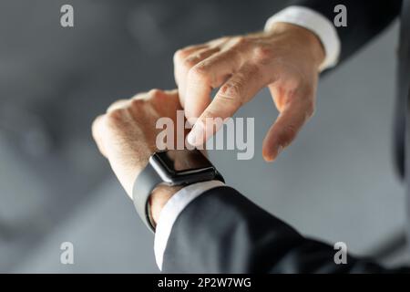 Smart devices. Unrecognizable businessman pressing blank screen on smartwatch on his hand, cropped, mockup Stock Photo