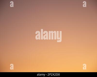 Orange sunset sky background. Natural color gradient in the clear sky. Smooth light transition with beautiful glow in the evening. Stock Photo