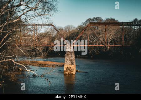 Dowhait's Bridge, a rusted old train and car bridge with a river flowing underneath the rusted red bridge. Stock Photo