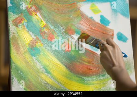 Hand of young woman touching canvas with paintbrush Stock Photo