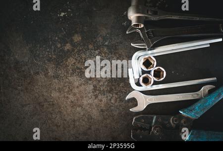 Hand tools consisting of wrenches, pliers, socket wrenches, laid out on old steel plate background. Stock Photo