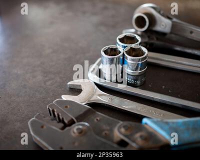 Hand tools consisting of wrenches, pliers, socket wrenches, laid out on old steel plate background. Stock Photo