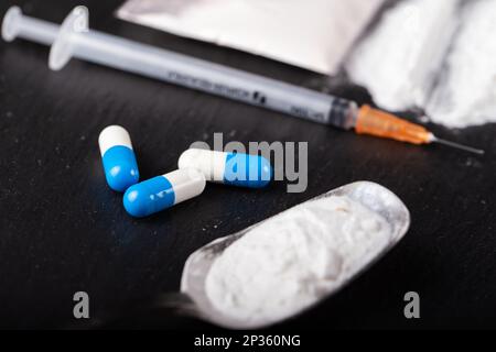 Drugs and dollars on a black background. Syringe, drug powder and tablets Stock Photo